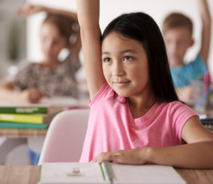 Teenage student raising hand in classroom